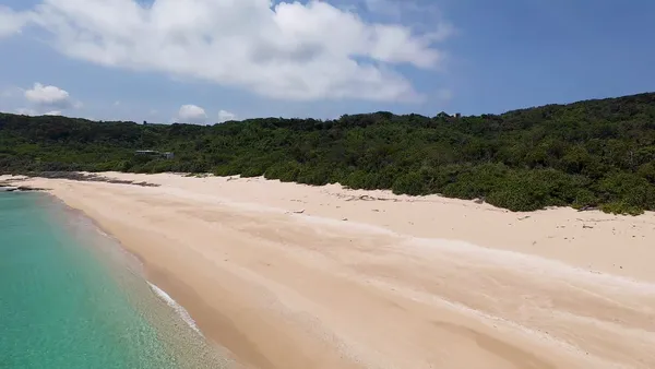 Drone beach with white sand and green hills
